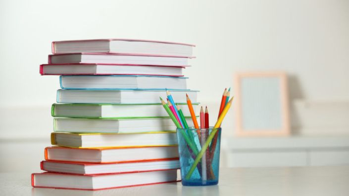 Colorful books and pencil on table in room